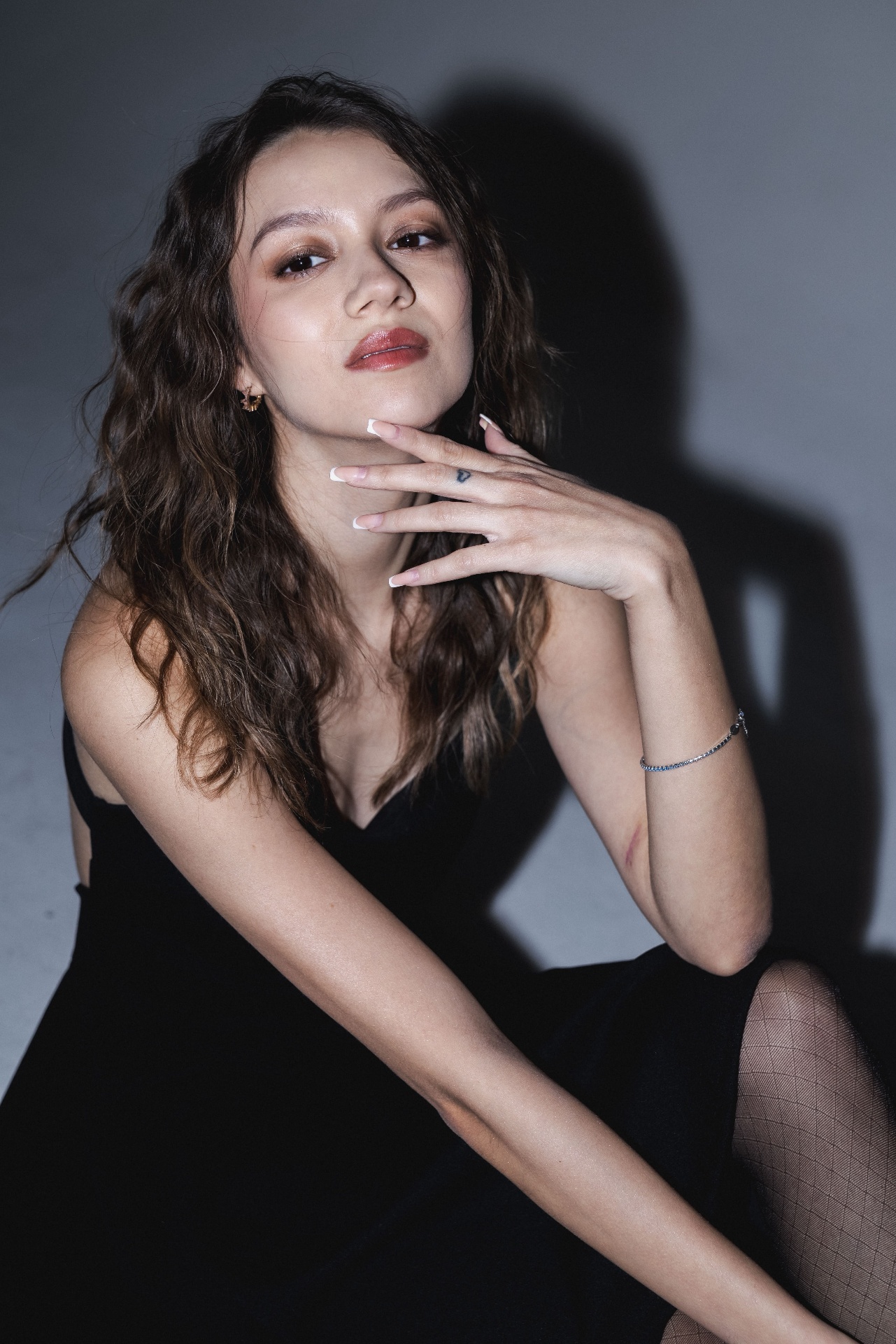 Seated portrait with hand at the chin in a black dress