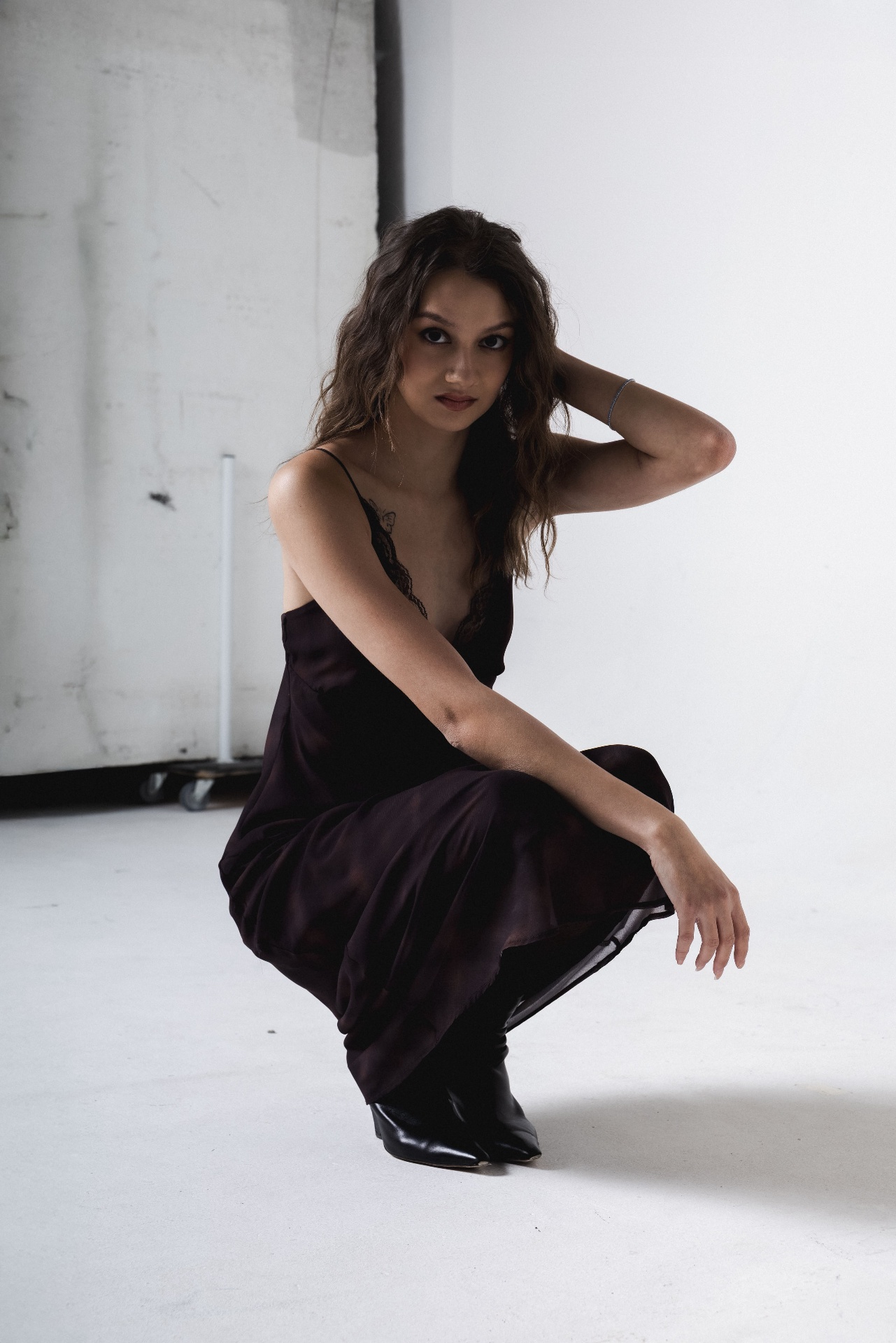 Crouching in a plum slip dress, hand in hair