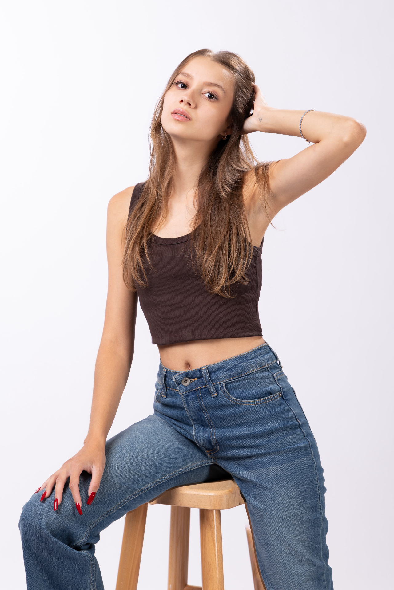 Seated on a stool in a brown crop top and jeans