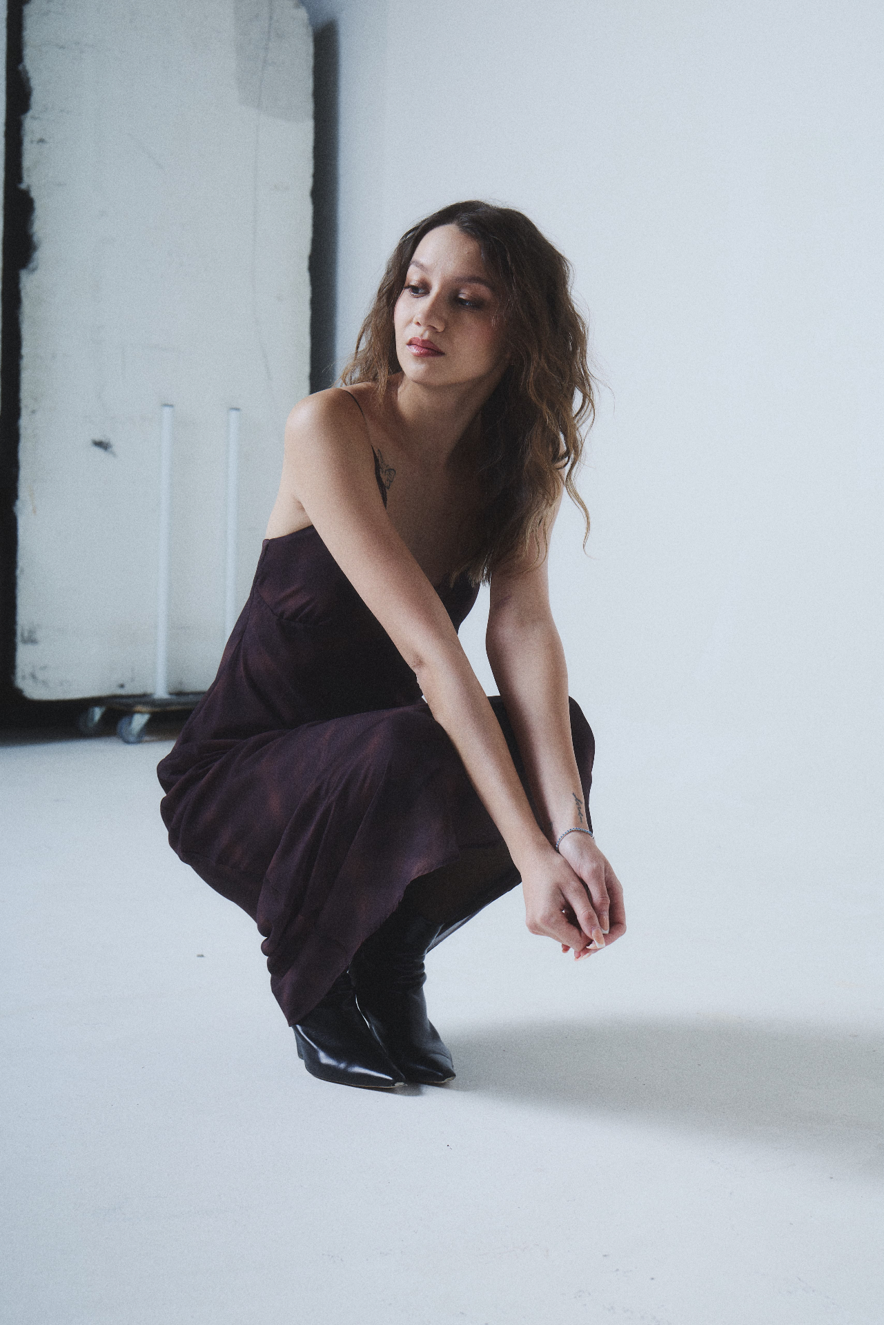 Crouching pose in a plum slip dress in the studio