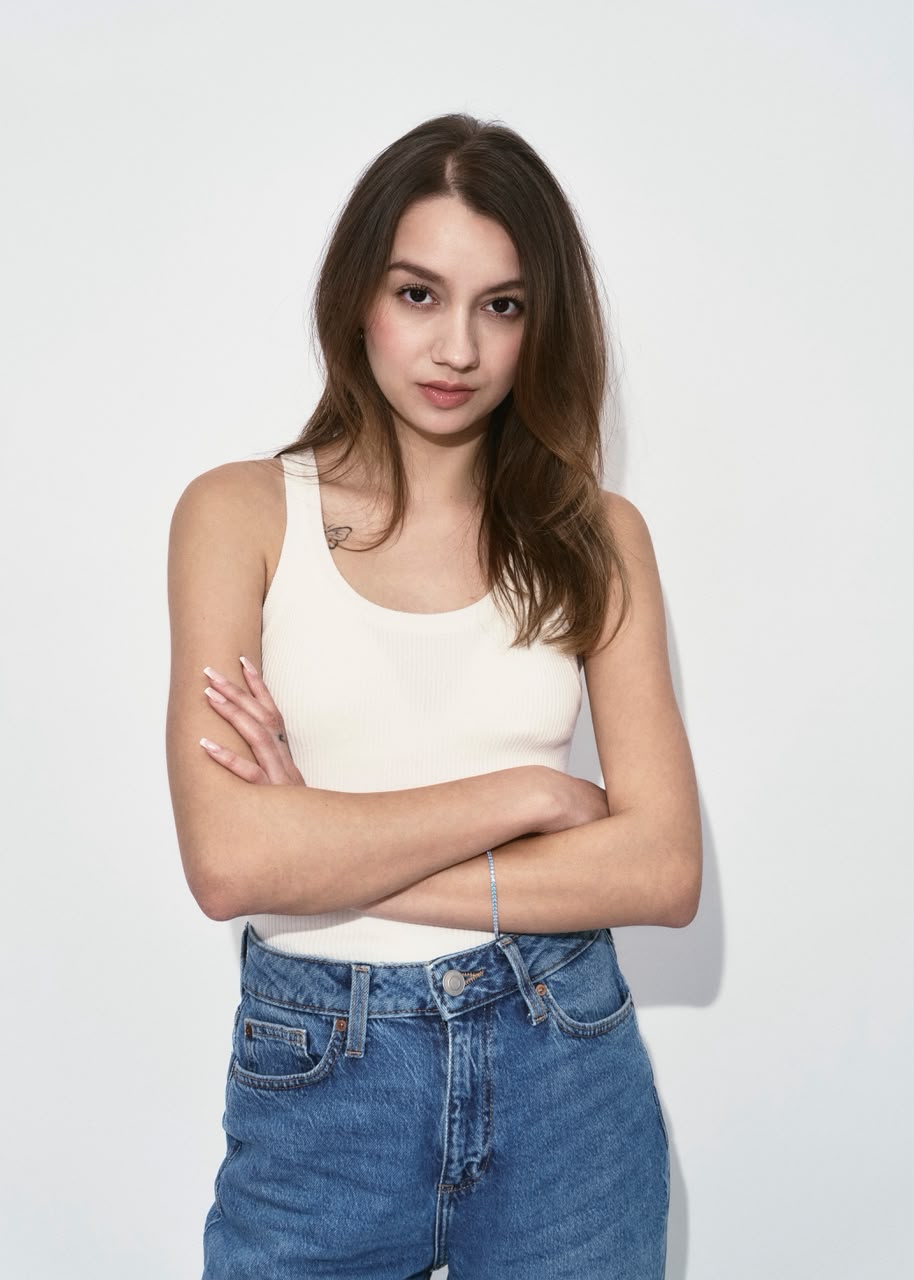 Arms crossed in a cream tank and denim